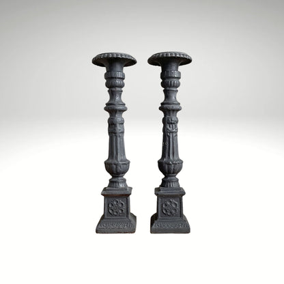 A pair of vintage, ornate dark grey wooden candle holders.