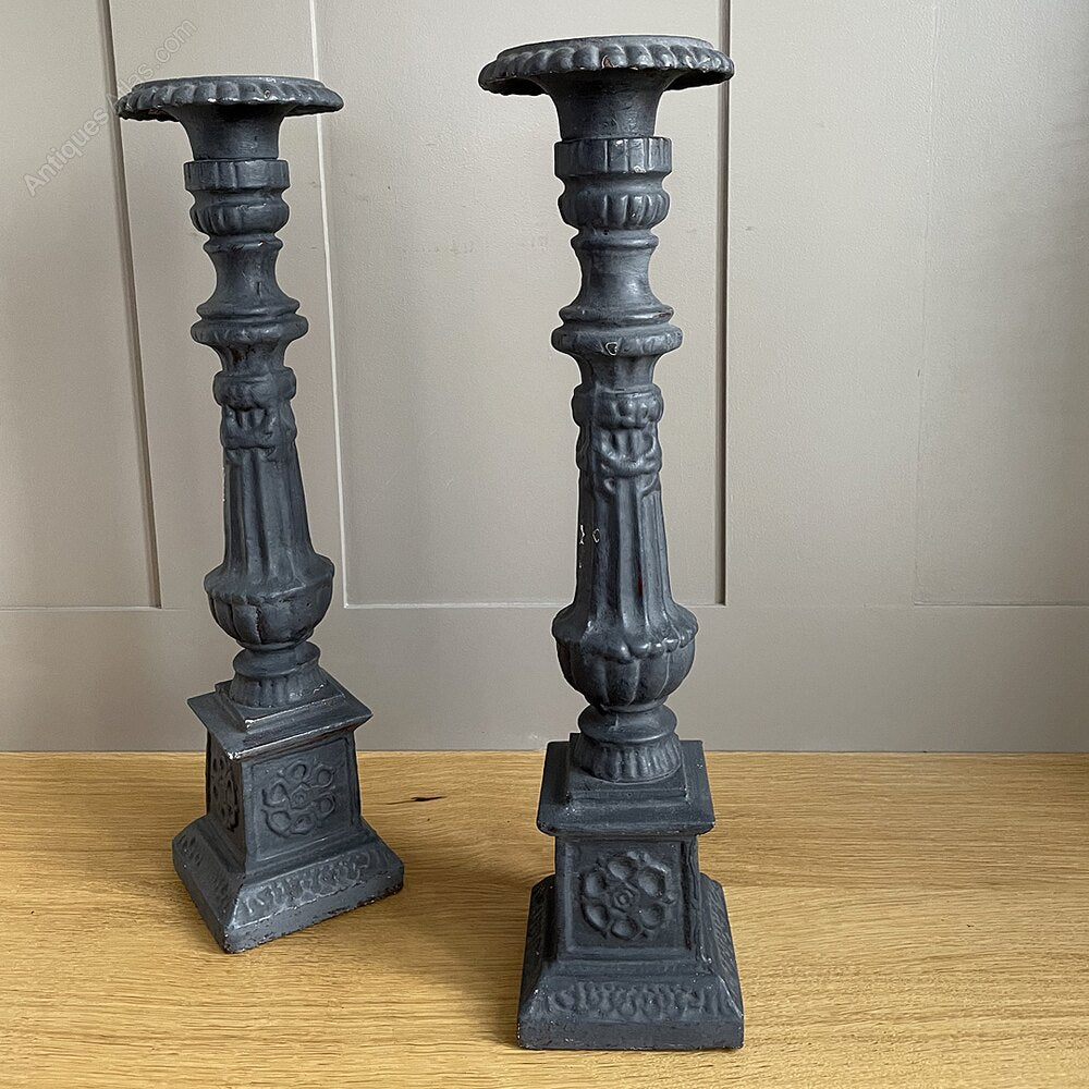 A pair of vintage, ornate dark grey wooden candle holders.