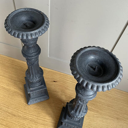 A pair of vintage, ornate dark grey wooden candle holders.