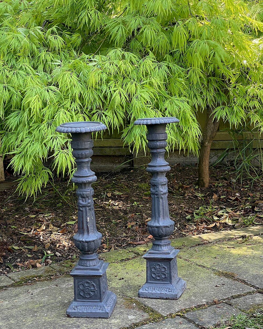 A pair of vintage, ornate dark grey wooden candle holders.
