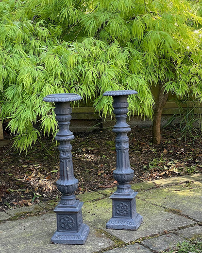 A pair of vintage, ornate dark grey wooden candle holders.