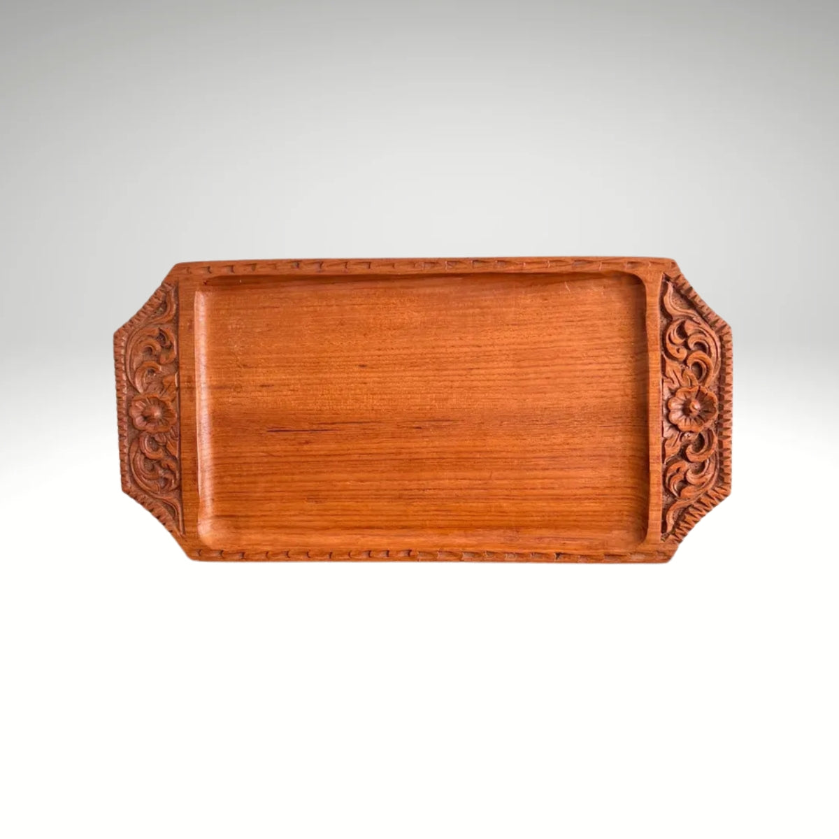 A rectangular wooden serving tray with detailed floral carvings on both handles