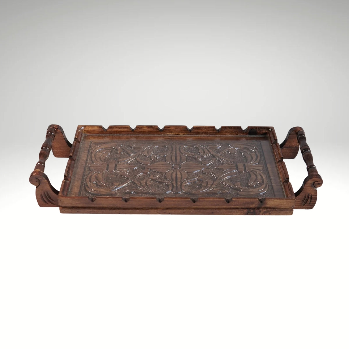 A rectangular wooden serving tray with detailed floral carvings on both handles and a smooth natural grain finish.
