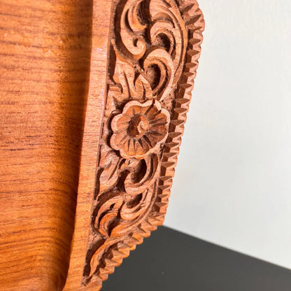 A rectangular wooden serving tray with detailed floral carvings on both handles