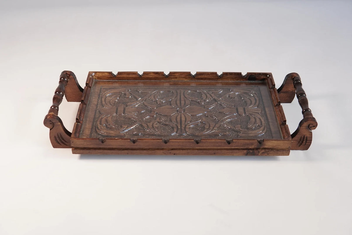 A rectangular wooden serving tray with detailed floral carvings on both handles and a smooth natural grain finish.