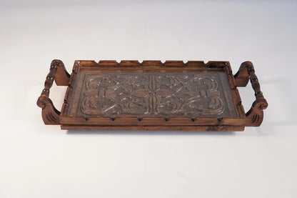 A rectangular wooden serving tray with detailed floral carvings on both handles and a smooth natural grain finish.