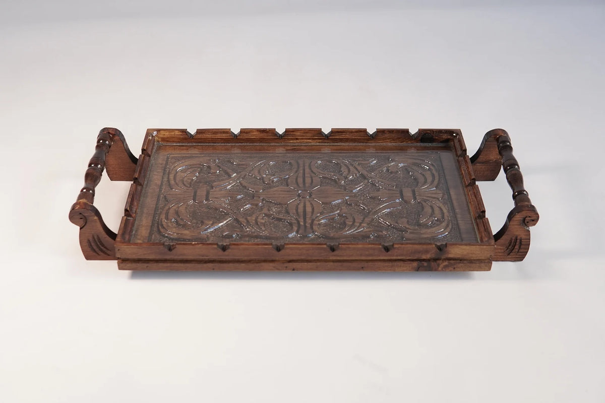 A rectangular wooden serving tray with detailed floral carvings on both handles and a smooth natural grain finish.