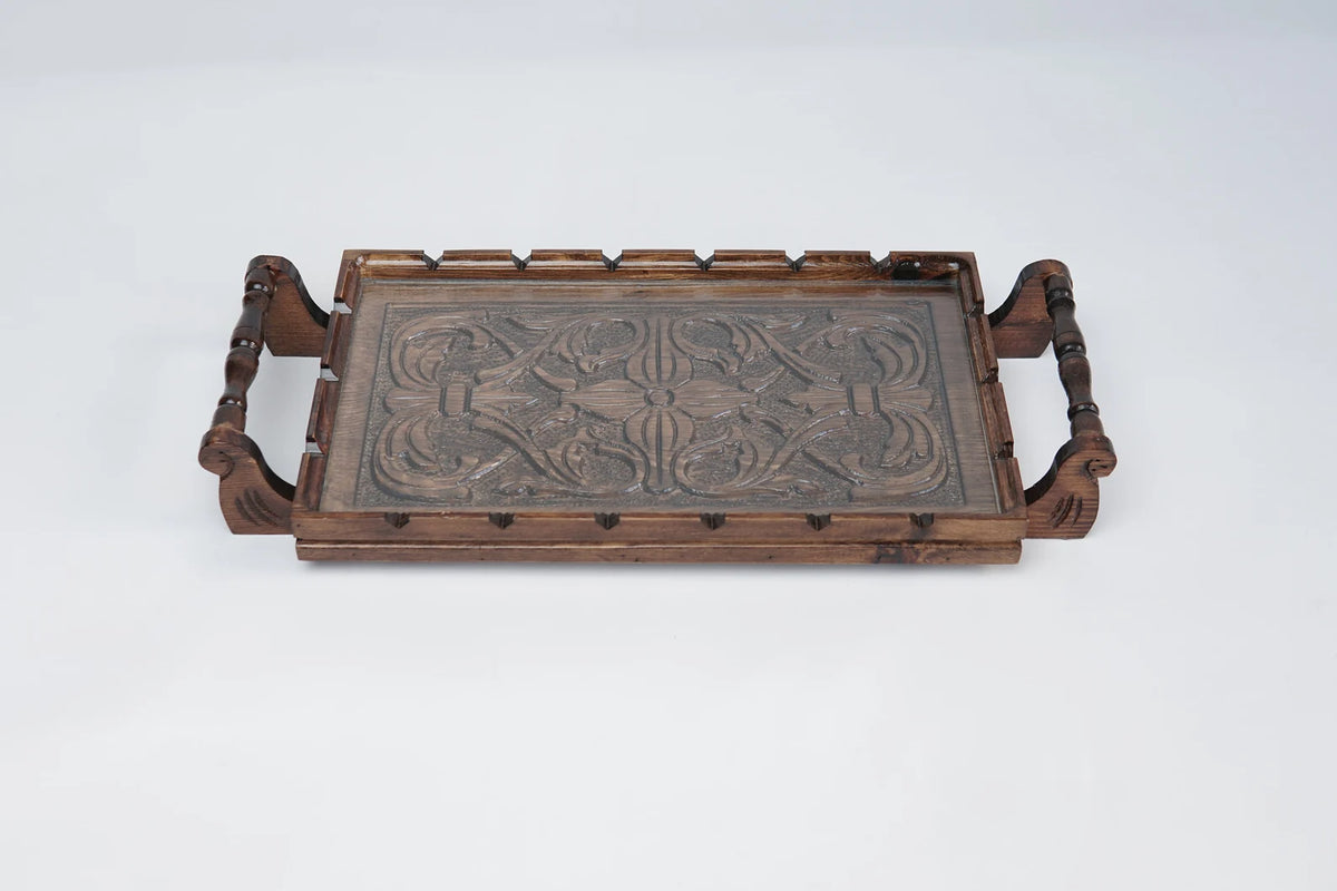 A rectangular wooden serving tray with detailed floral carvings on both handles and a smooth natural grain finish.