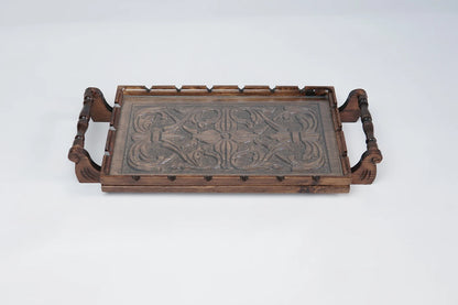 A rectangular wooden serving tray with detailed floral carvings on both handles and a smooth natural grain finish.