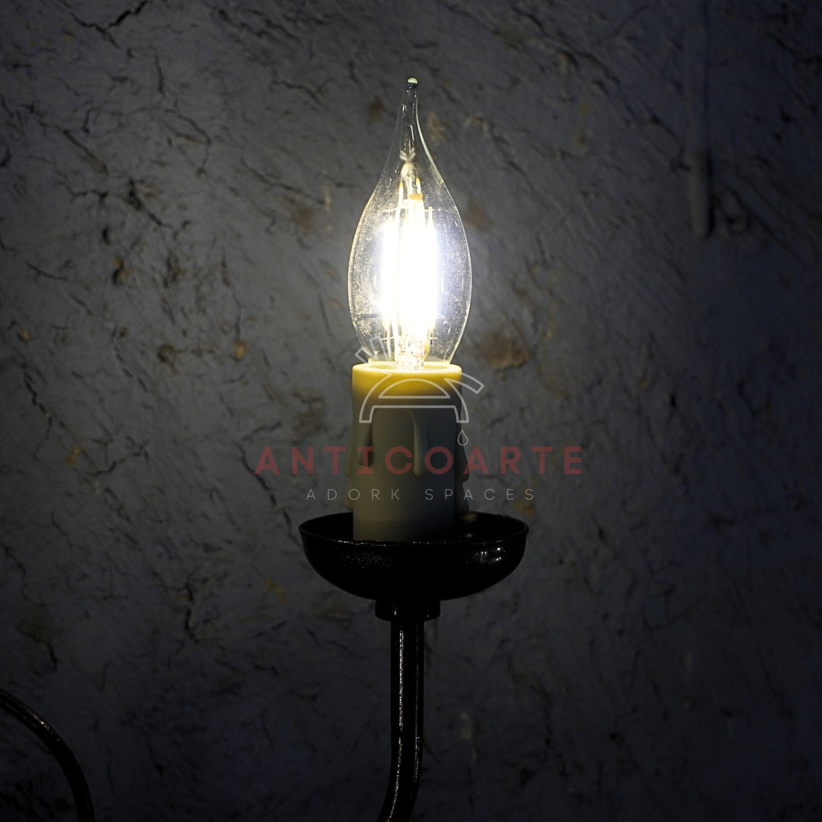A rustic double-light wall sconce with a decorative dark metal scrollwork frame and two glowing cream fabric lampshades.