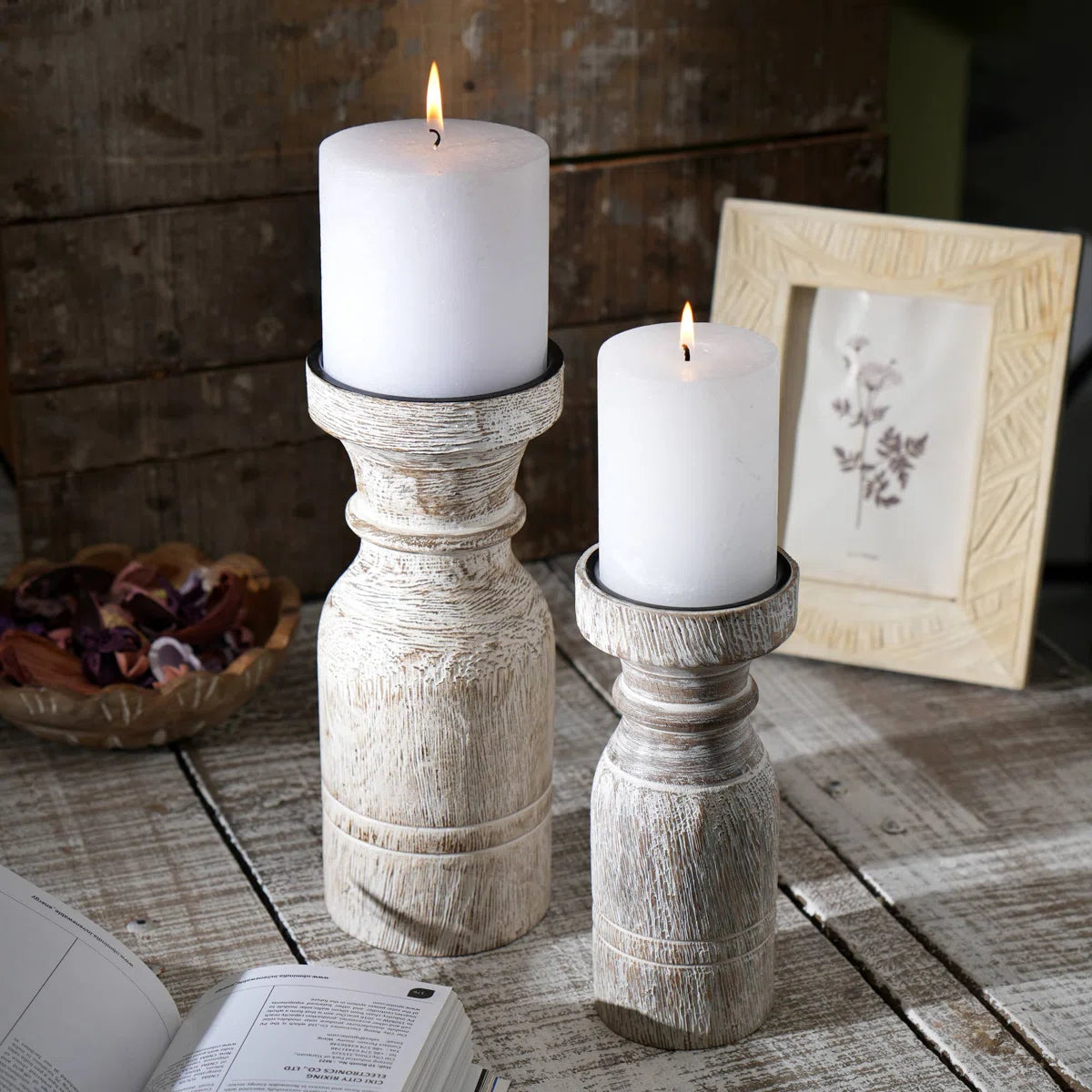 A rustic whitewashed wooden pillar candle holder with a distressed finish