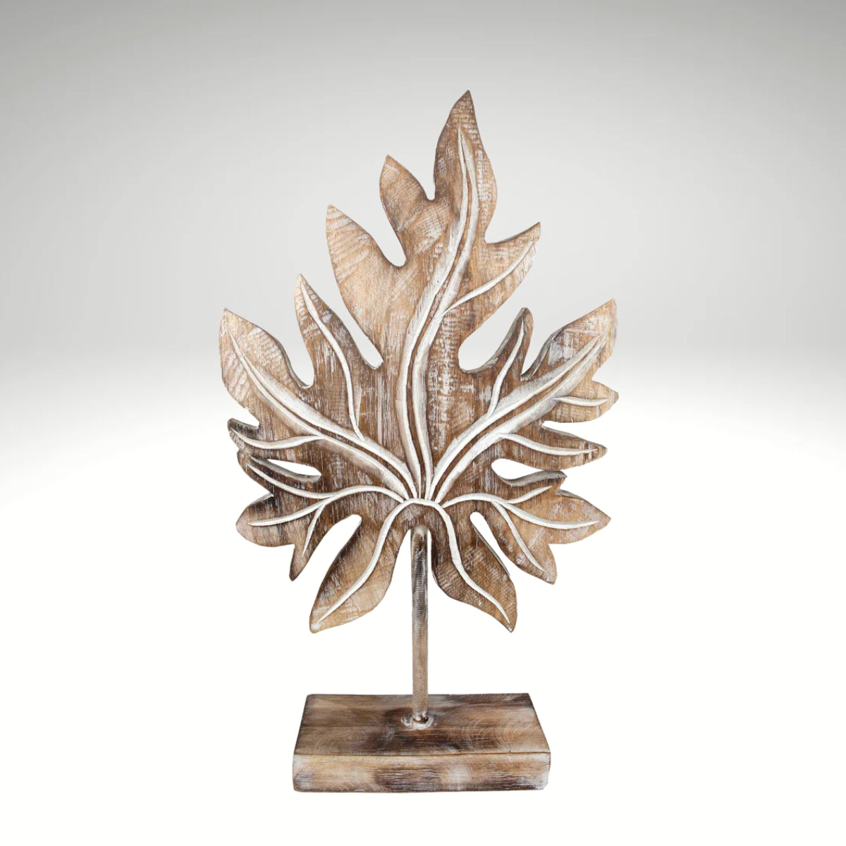 Carved wooden tropical leaf sculpture on a stand.