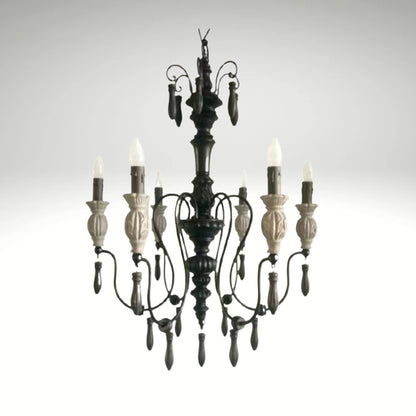 Rustic gothic-inspired wrought iron chandelier featuring carved details and flame-tip lights.