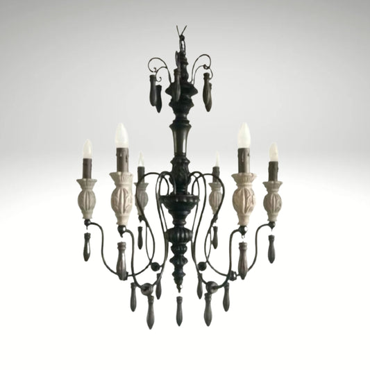 Rustic gothic-inspired wrought iron chandelier featuring carved details and flame-tip lights.