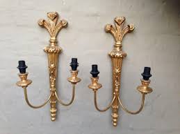 Ornate vintage brass wall lamp with two arms and a detailed gold finish