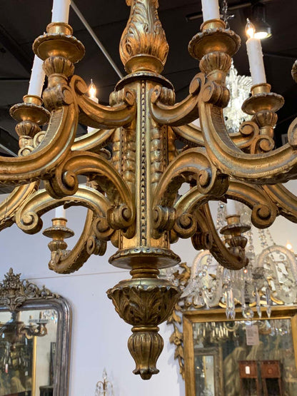Vintage-style gilded wooden chandelier with detailed carvings, a central baluster stem, and ten electric candle sleeve lights.