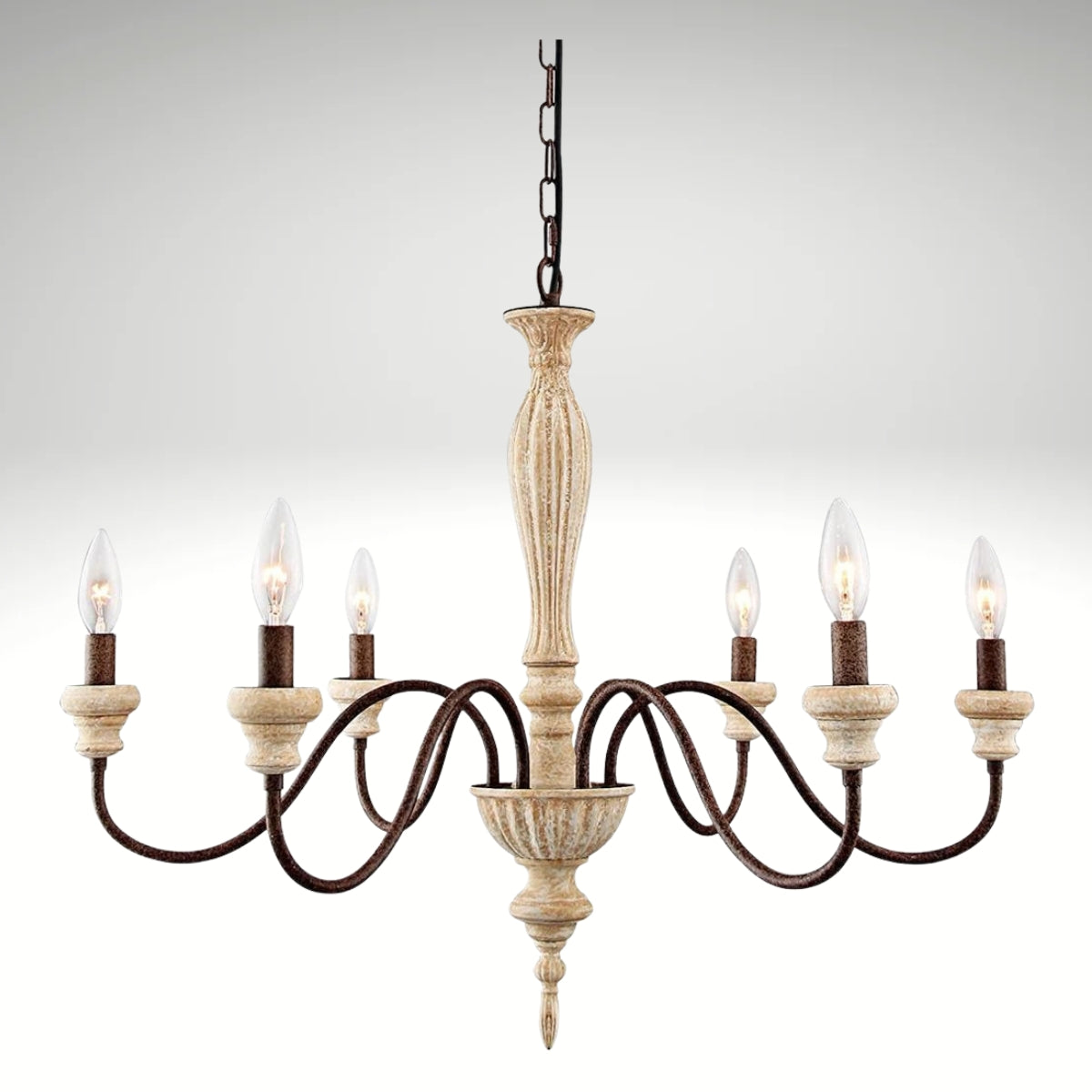 An elegant antique-style metal chandelier featuring sweeping curved arms, candle-style bulbs, and decorative crystal pendants illuminated by warm yellow light.