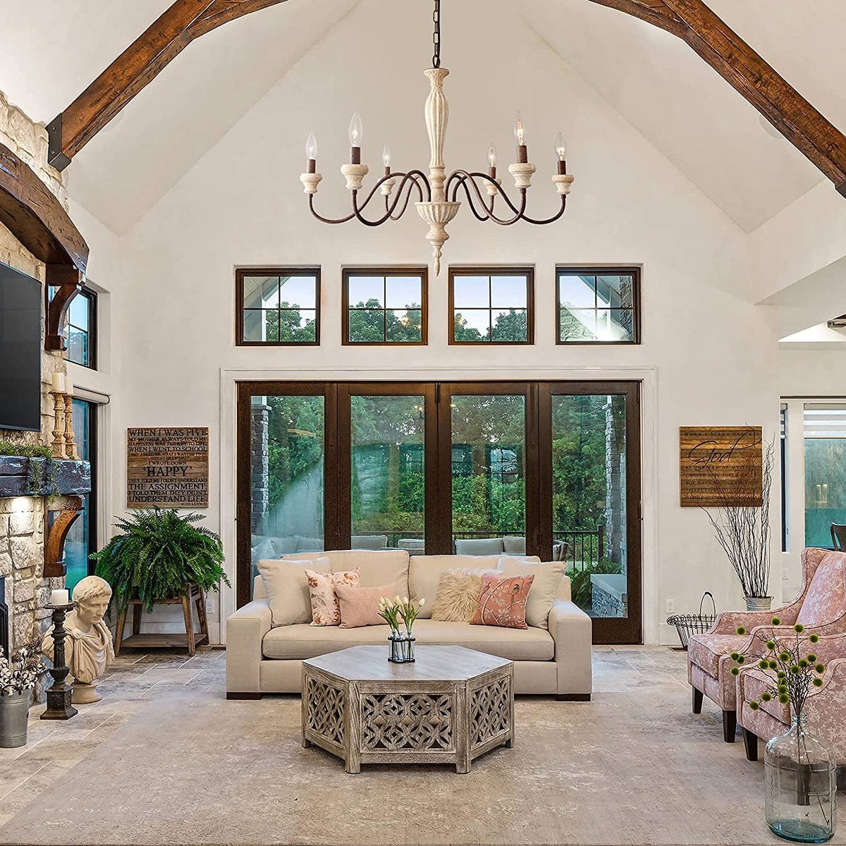 An elegant antique-style metal chandelier featuring sweeping curved arms, candle-style bulbs, and decorative crystal pendants illuminated by warm yellow light.
