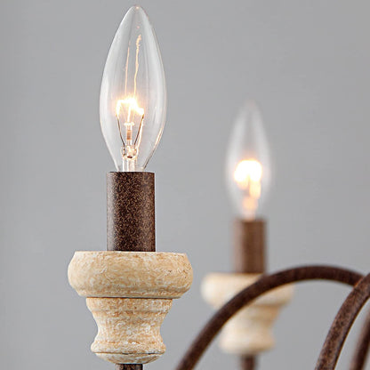 An elegant antique-style metal chandelier featuring sweeping curved arms, candle-style bulbs, and decorative crystal pendants illuminated by warm yellow light.