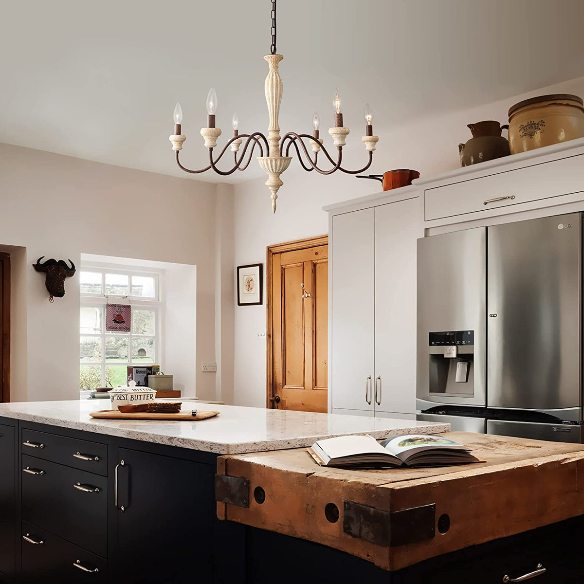 An elegant antique-style metal chandelier featuring sweeping curved arms, candle-style bulbs, and decorative crystal pendants illuminated by warm yellow light.