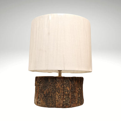 A bohemian-style desk lamp crafted from a blocky, distressed wood baluster and a natural straw woven shade.