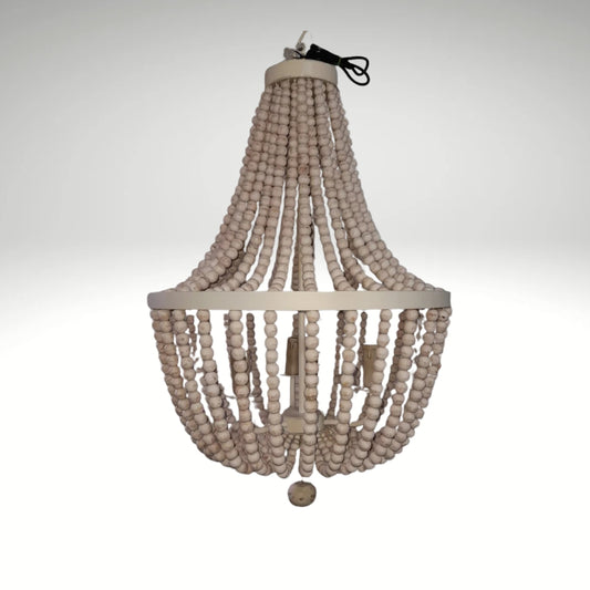 A rustic boho chandelier made of cascading strands of white wooden beads hung from a circular metal frame.