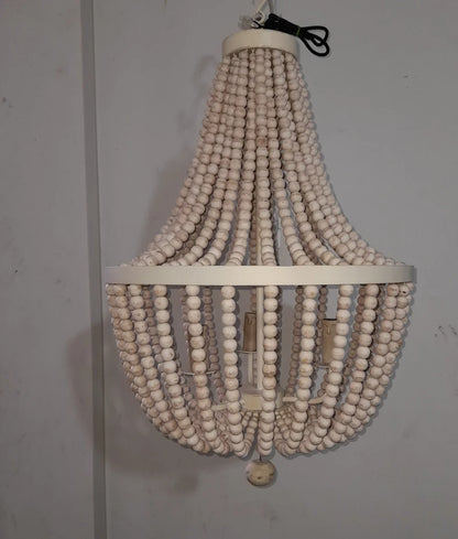 A rustic boho chandelier made of cascading strands of white wooden beads hung from a circular metal frame.
