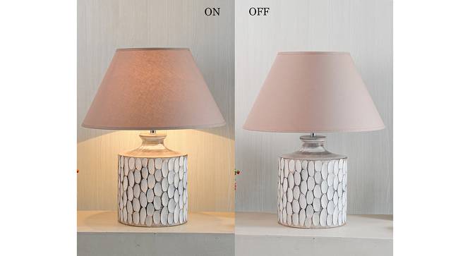 A rustic white ceramic table lamp featuring a textured, carved oval pattern on a cylindrical base with a beige fabric shade.