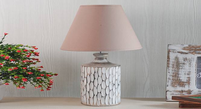 A rustic white ceramic table lamp featuring a textured, carved oval pattern on a cylindrical base with a beige fabric shade.