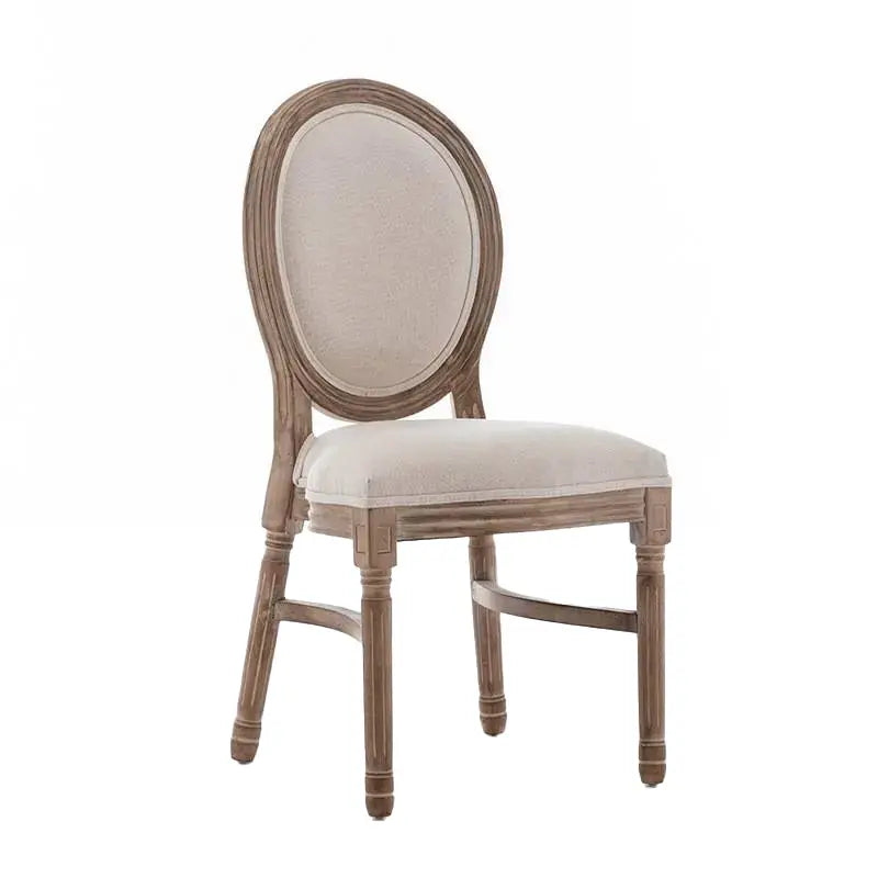 A rustic French country dining chair featuring an oval upholstered backrest and a weathered wooden frame.