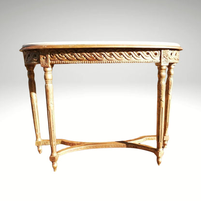 Giltwood console table with a marble top and fluted legs, placed outdoors on a stone patio.