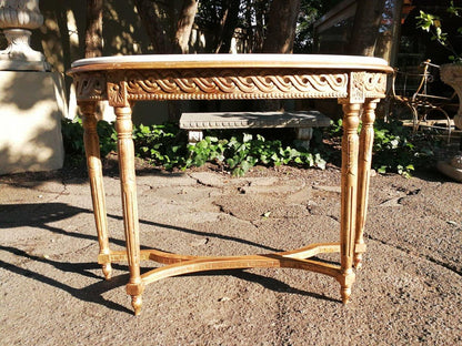 Giltwood console table with a marble top and fluted legs, placed outdoors on a stone patio.