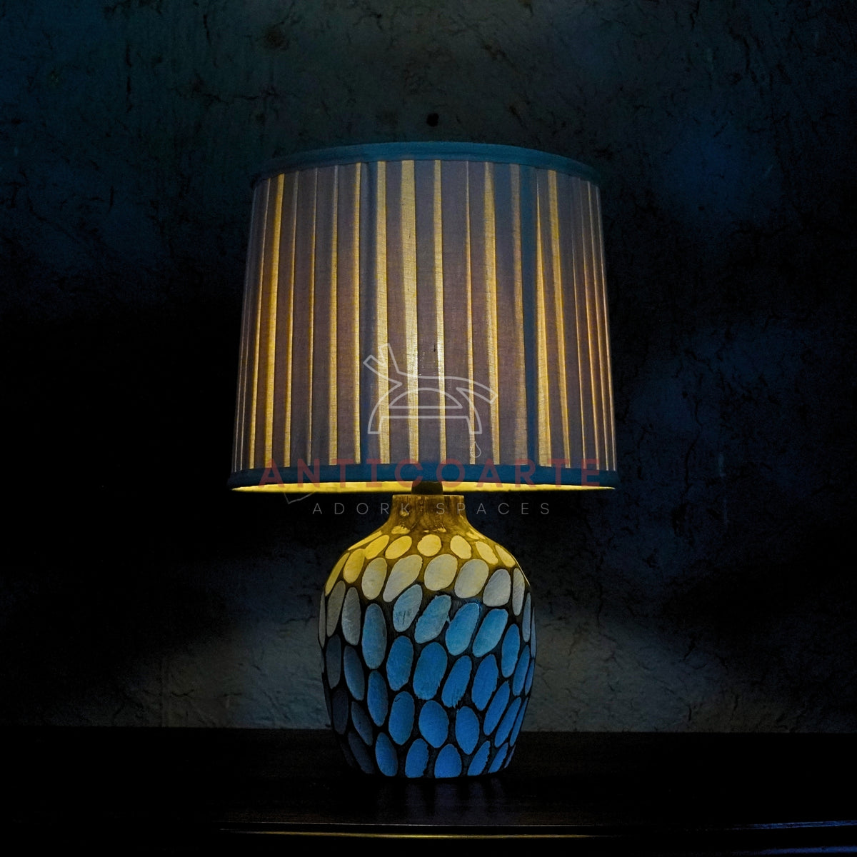 Modern table lamp with a textured mosaic pattern base and a pleated white lampshade