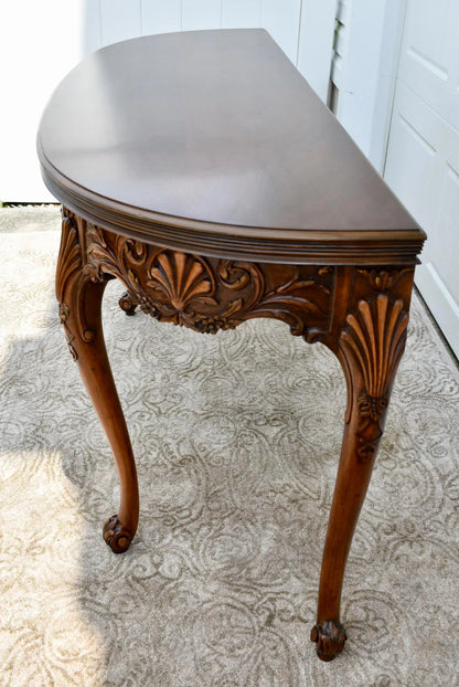 Vintage carved wooden half-moon console table with ornate details and curved legs.