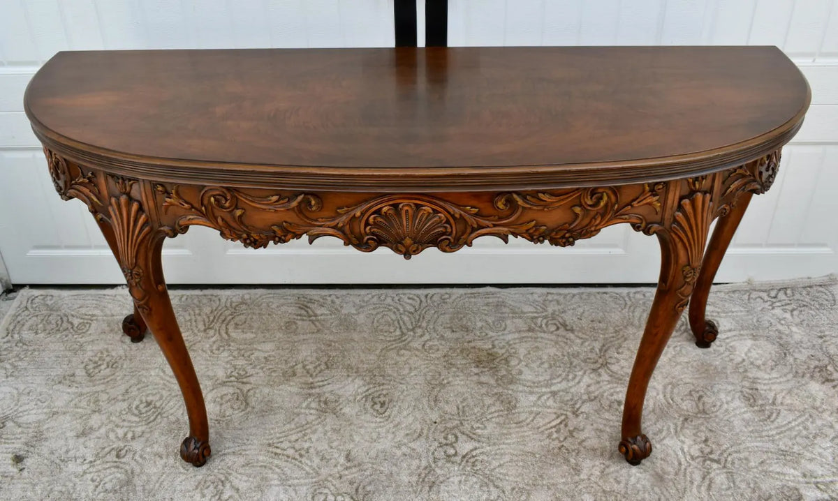 Vintage carved wooden half-moon console table with ornate details and curved legs.