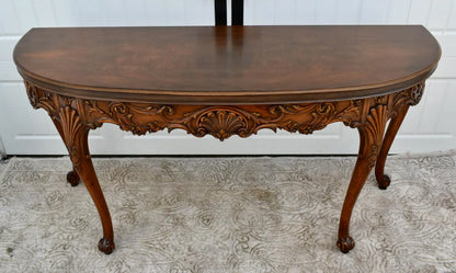 Vintage carved wooden half-moon console table with ornate details and curved legs.