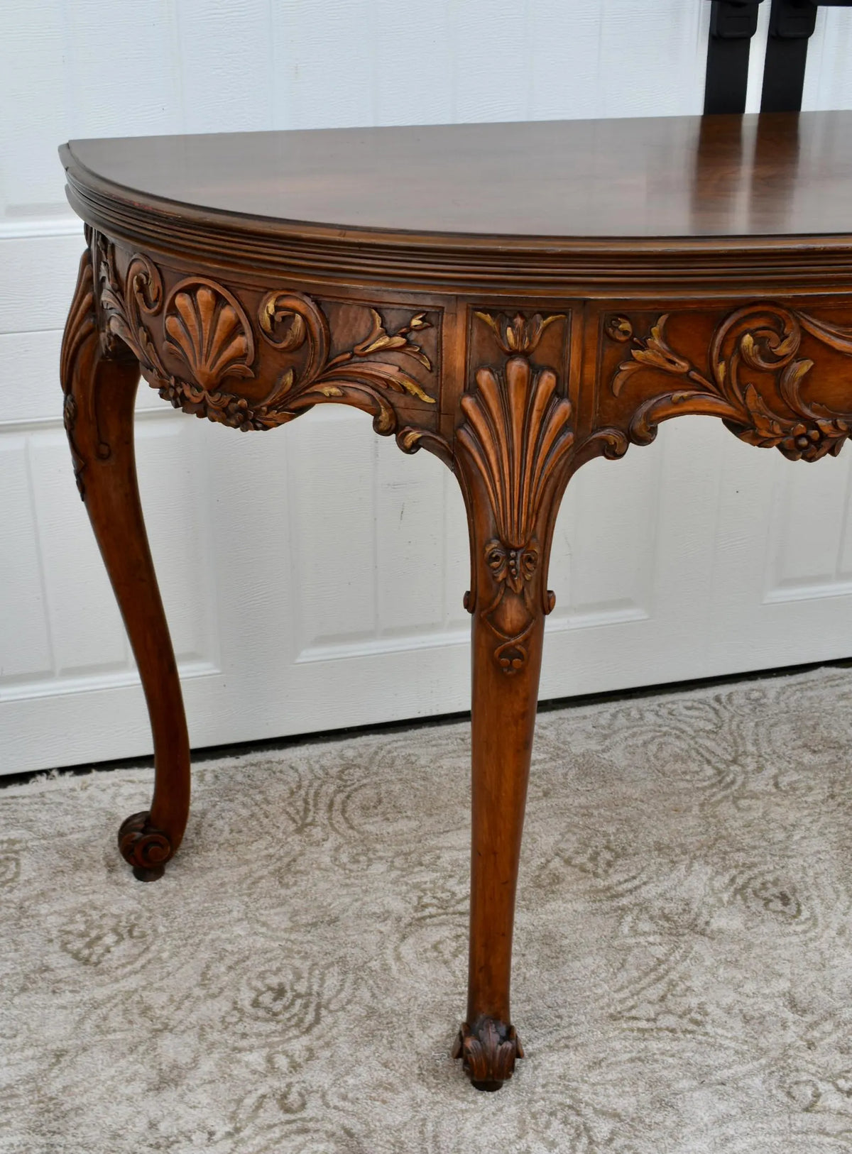 Vintage carved wooden half-moon console table with ornate details and curved legs.