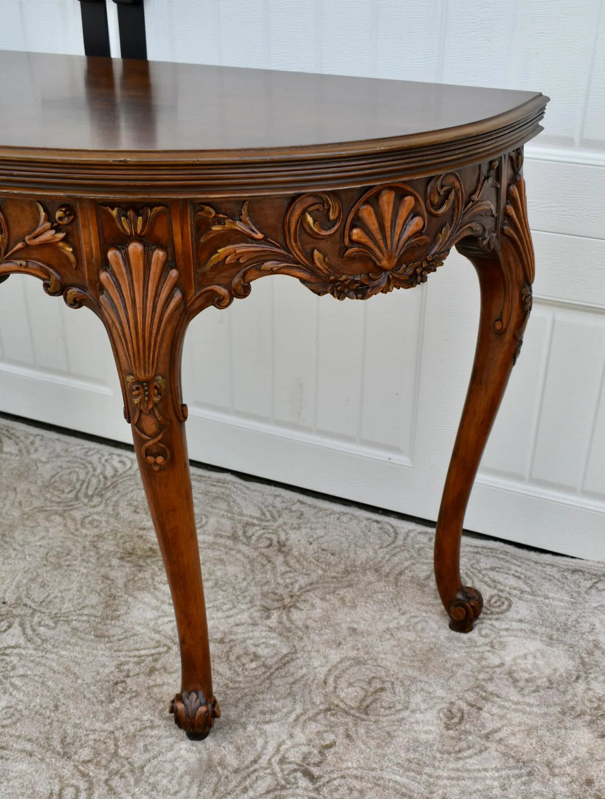Vintage carved wooden half-moon console table with ornate details and curved legs.