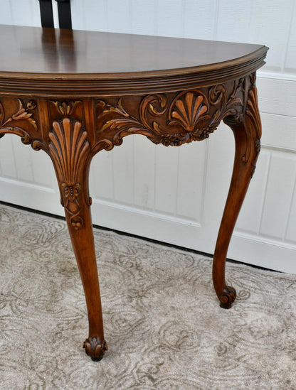 Vintage carved wooden half-moon console table with ornate details and curved legs.