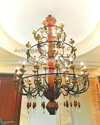 Large vintage-style antique chandelier with multiple layers of warm lights shaped like blooming flowers and decorative metal framing.