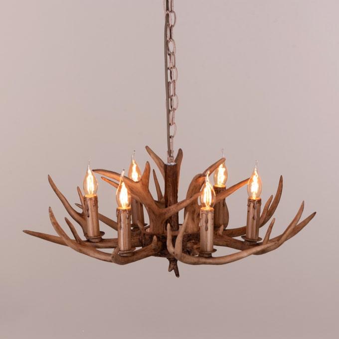 Faux antler pendant light with three lit candle-style bulbs, country style design.
