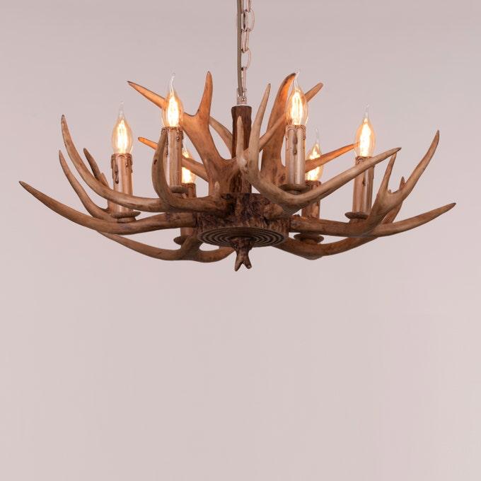 Faux antler pendant light with three lit candle-style bulbs, country style design.