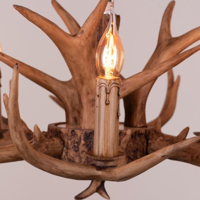 Faux antler pendant light with three lit candle-style bulbs, country style design.