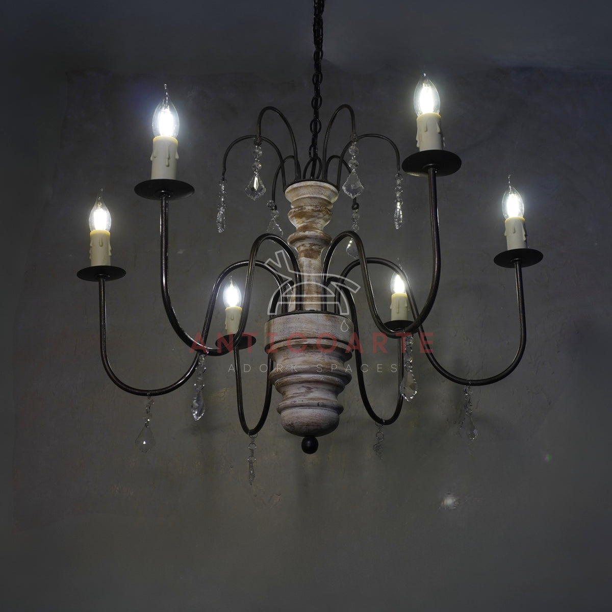 Rustic 6-light candle chandelier with a distressed white wood spindle, curved bronze metal arms, and hanging crystal accents.