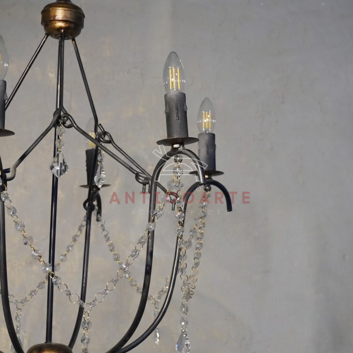 A 6-light candle-style chandelier featuring a black wrought iron cage frame, distressed bronze hardware accents, and delicate hanging crystal bead chains with teardrop pendants.