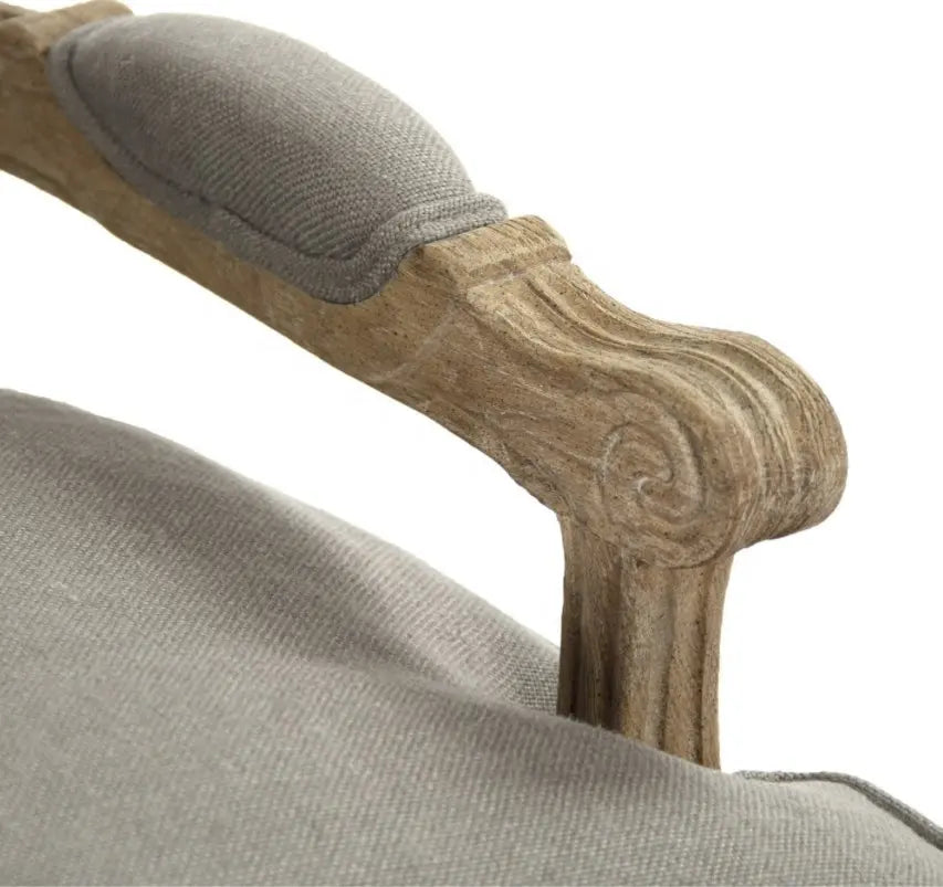 A classic French country style armchair with a weathered natural wood frame and comfortable grey linen upholstered cushions.
