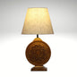 Bohemian-style table lamp with a round, carved wood mandala base and a neutral fabric lampshade