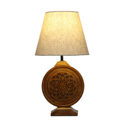 Bohemian-style table lamp with a round, carved wood mandala base and a neutral fabric lampshade