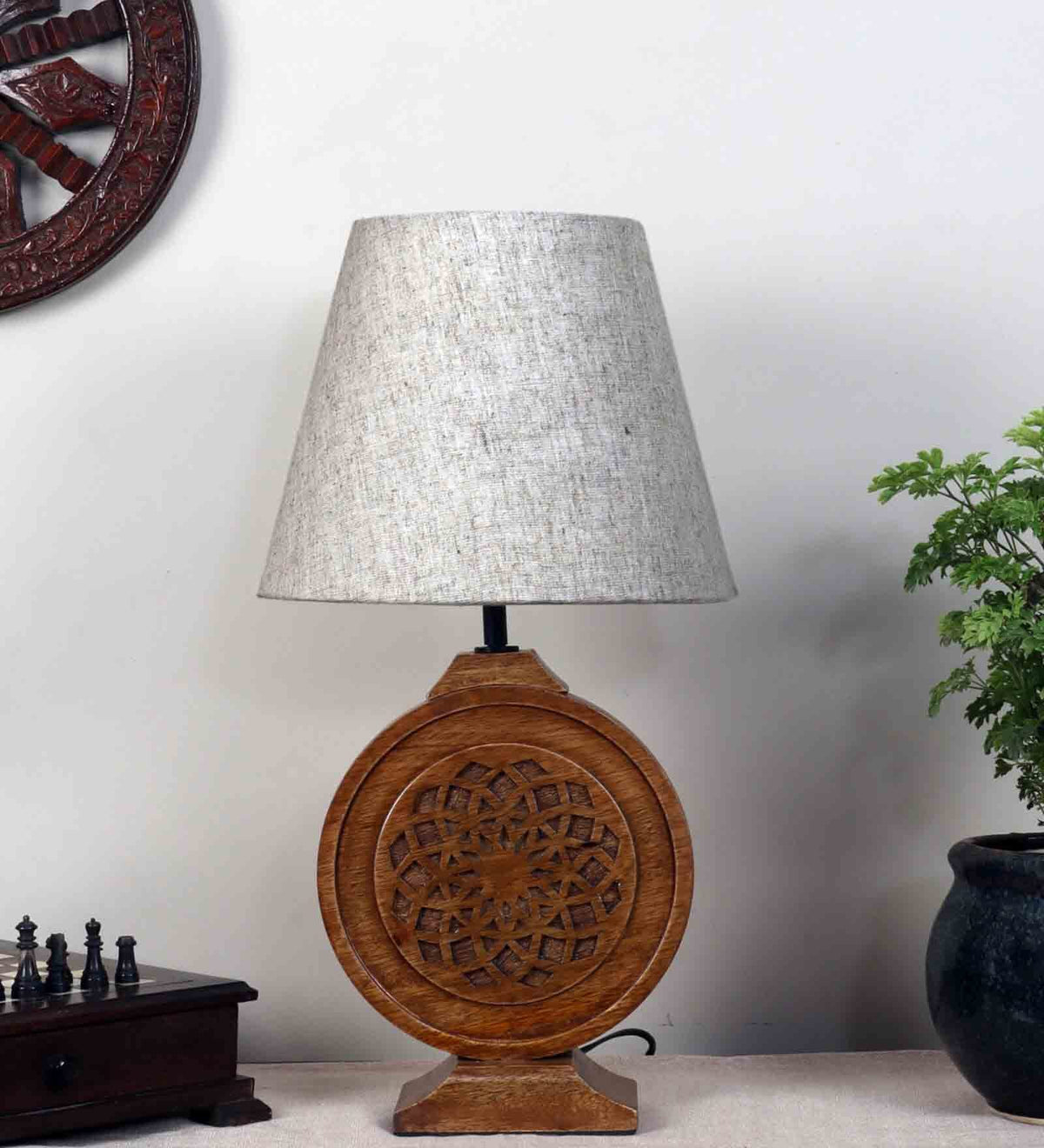 Bohemian-style table lamp with a round, carved wood mandala base and a neutral fabric lampshade