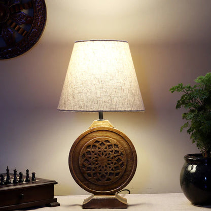 Bohemian-style table lamp with a round, carved wood mandala base and a neutral fabric lampshade